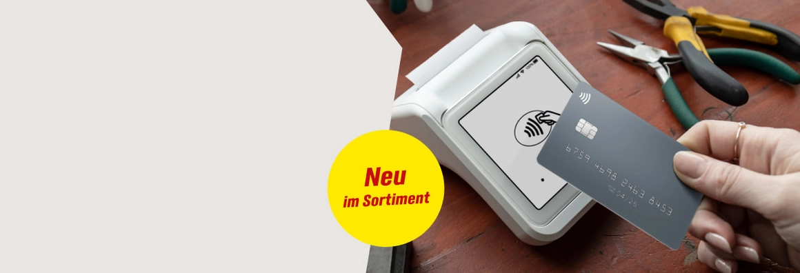 Neu im Sortiment. Eine Hand hält eine Karte zum kontaktlosen Bezahlen an ein Lesegerät.